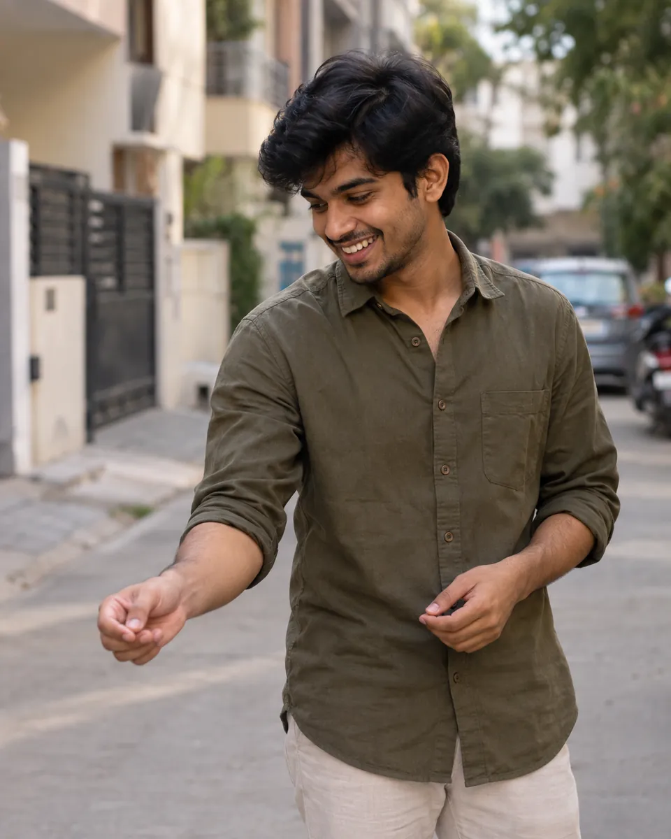 Smiling young man in an olive shirt walking down a quiet residential street in daylight.