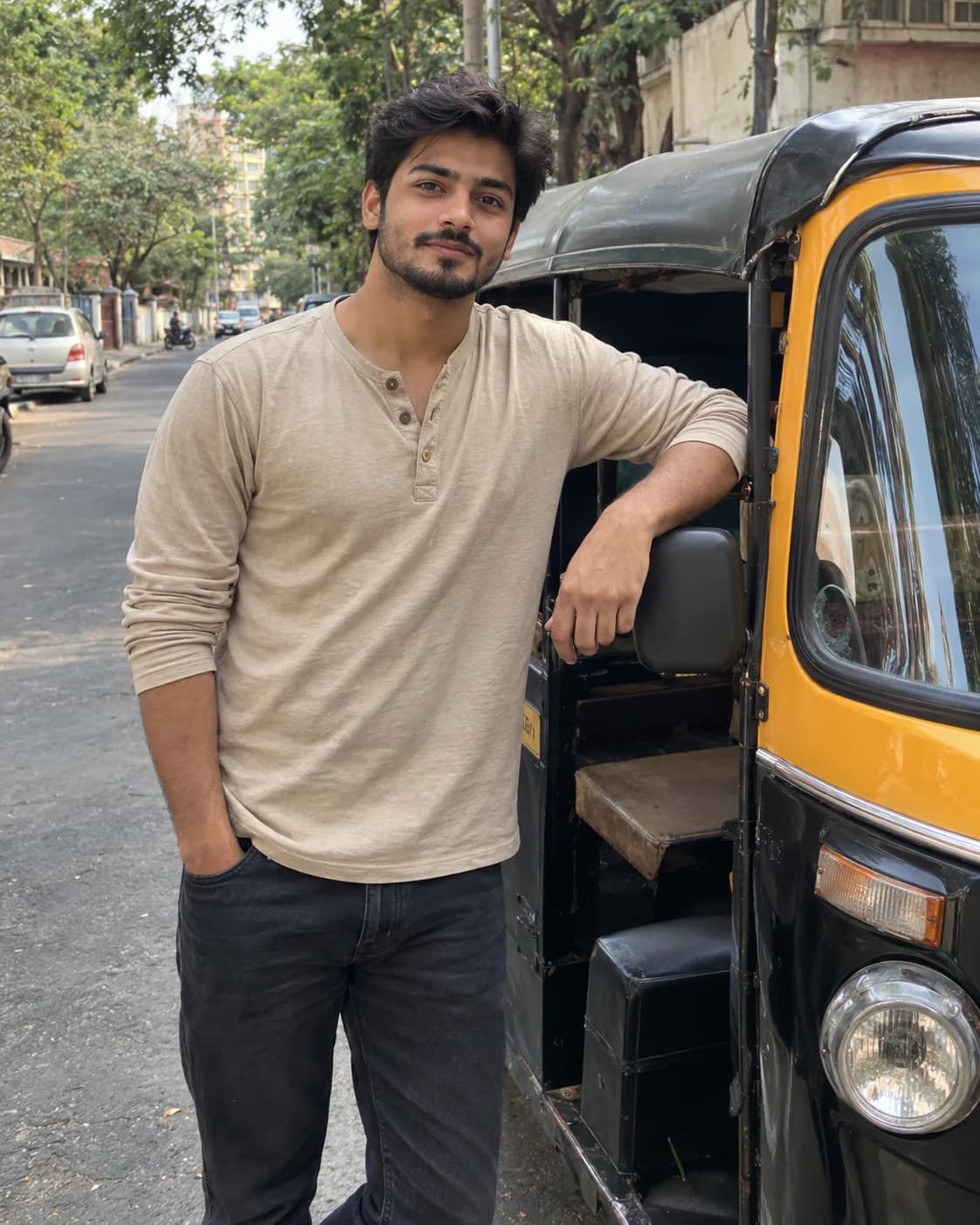 Bearded man in a beige henley leaning on a black-and-yellow auto-rickshaw.